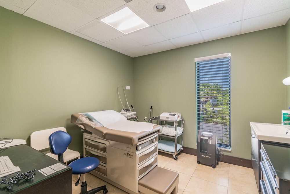 Medical facility room with examination table, desk, and medical supplies